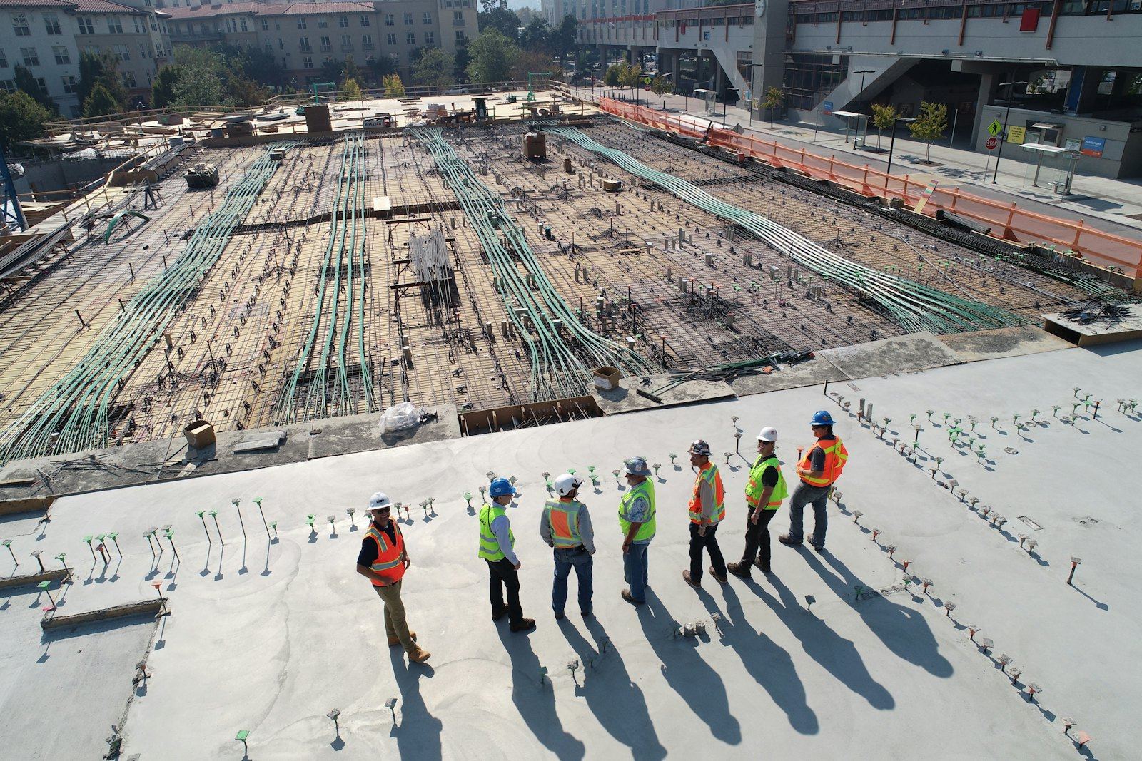 Aerial view of a construction site with workers in hard hats beside steel reinforcement