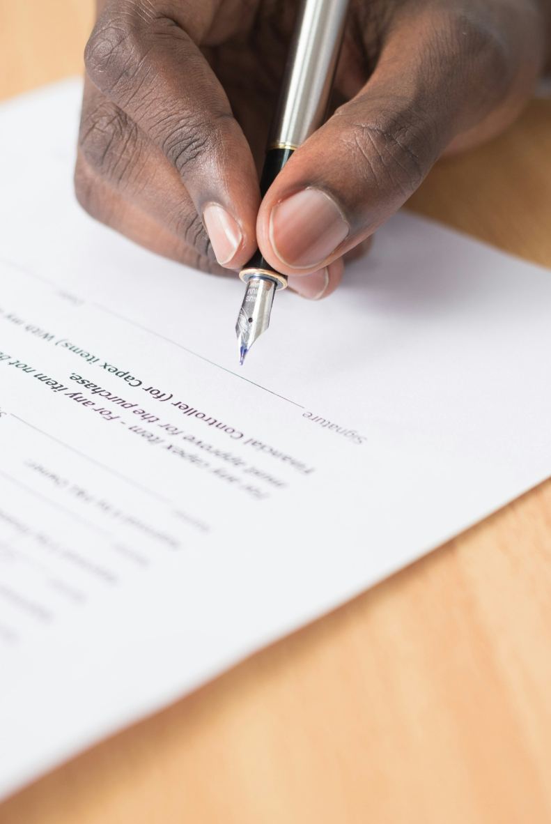 A hand signing a legal document with a fountain pen
